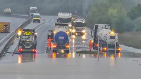 Ten large vehicles with lights on helping to pump water floodwater