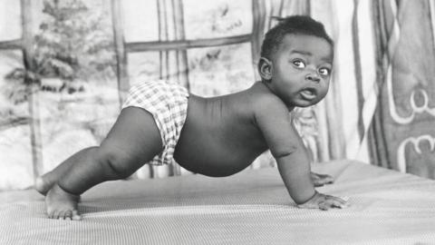 A black and white photo of a baby on all fours