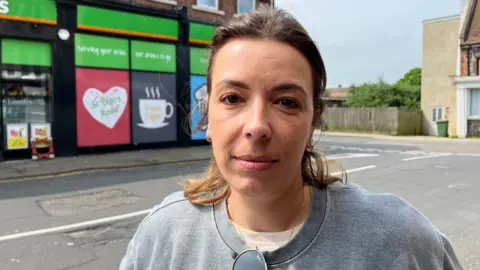 Andrew Turner/BBC Carla Carvalho standing outside the Londis shop on St Peter's Road