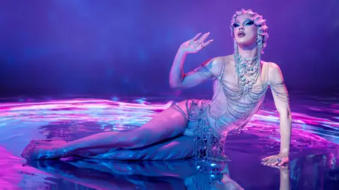 @gregbaileyphoto A drag queen in a diamond dress laying down