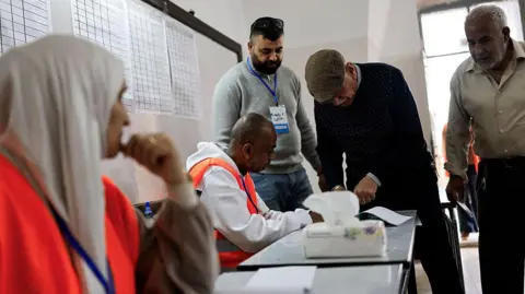 Getty Images Voters taking and election officials speaking at a polling station in Jenin
