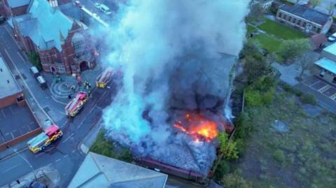 An aerial view of the social club alight with thick smoke in the air