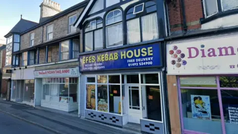 A parade of shops, including the Efes Kebab House, the sign for which has yellow writing against a blue background. 