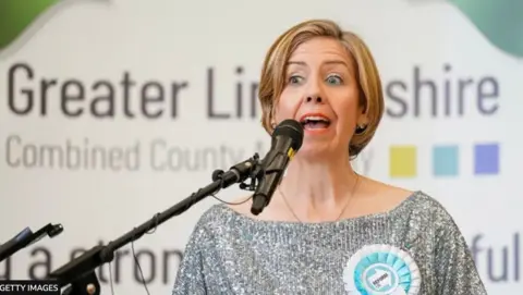 Getty Images Dame Andrea Jenkyns. She is speaking into a microphone in front of a banner which reads Greatesr Lincolnshire Combined Authority. She wears a silver top and a rosette in the light blue colour of Reform UK.