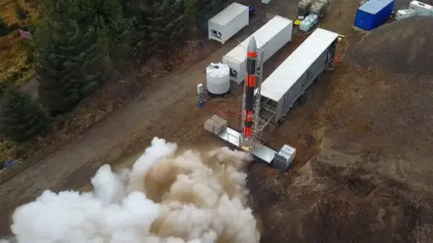 Smoke emerges from the engines of a rocket on a temporary launch site in the Highlands.