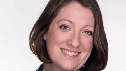 Dr Rachel Ward Dr Rachel Ward has medium length brown hair and is standing in front of a neutral background.