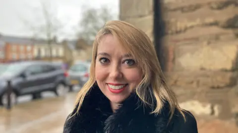 Laura Coffey/BBC Sarah Bool MP for South Northamptonshire wearing a black jacket she has blonde hair and is smiling at the camera
