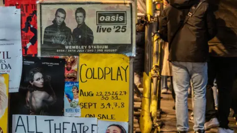 Getty Images People pass a poster advertising Oasis tickets for their London gigs on December 28, 2024 in London.