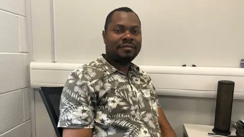 A man wearing a flowery shirt sat at a desk