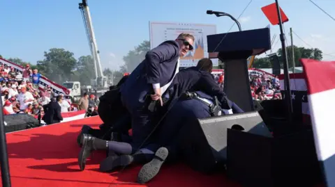 Getty Images  Secret service agents cover former president Donald Trump during a campaign rally for former President Donald Trump at Butler Farm Show Inc. on Saturday, July 13, 2024 in Butler, Pa