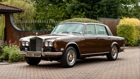 A burgundy vintage Rolls-Royce car parked on a driveway