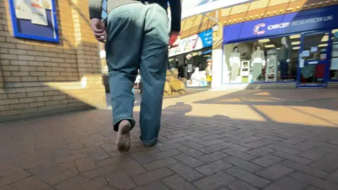 We see the dirty underside of Robert's foot as he walks through a shopping presinct in bourne