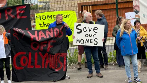 Protestors holding banners which say 'hands of Collyhurst' and 'Save our Homes'.