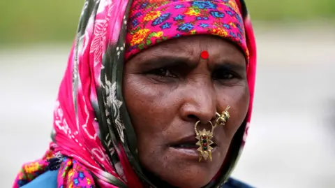 A Reuters Kali Devi, um trabalhador imigrante do Nepal, espera ao lado do heliporto de 3 anos, depois de ser atingido por um deslizamento de terra de seus filhos desaparecidos e parentes da religião, na vila de Bhatwadi, no norte do estado de Uttarakhand, em agosto de 2021.
