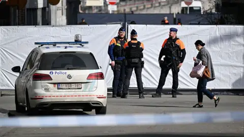 Police outside a cordon surrounding the scene of a bombing.
