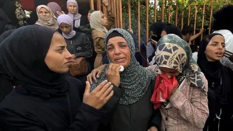 Mourners weep during the funeral of Palestinians killed in Israeli strikes on the southern Gaza Strip the previous day, outside the Nasser Hospital in Khan Yunis on July 4, 2025.