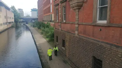 Two police officers stood on a canal towpath