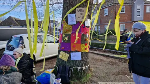 Campaigners sat and stood next to the oak tree, which has been covered in signage and yellow ribbons.