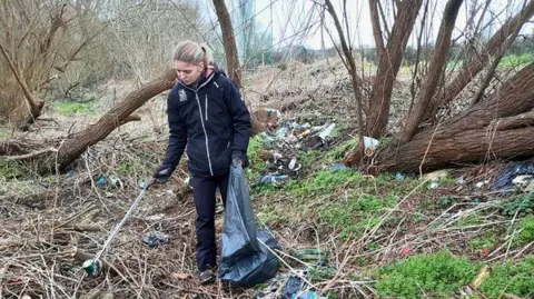 Des Smith A woman from the Wildlife Trust picking litter from an area that was full of rubbish.