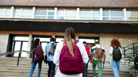 Studenti Getty Images, kteří chodí po krocích směrem k budově univerzity