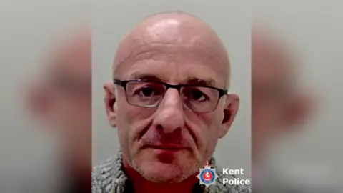 A police mug shot of a bald man. 