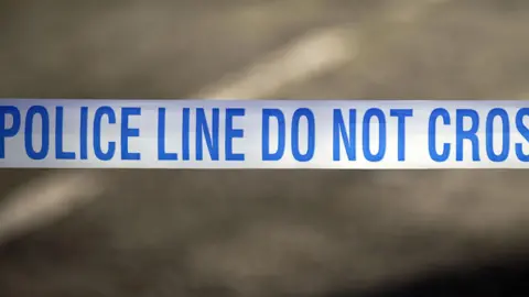 Peter Byrne/PA Blue and white police tape with the word Police line do not cross.