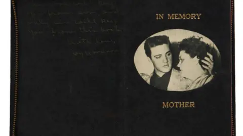 Sotheby's A black bible is seen, it's covers are spread out. One one side is a faint handwritten note whilst on the other side is a picture of Elvis and his mum under a text which reads 'IN MEMORY MOTHER'.