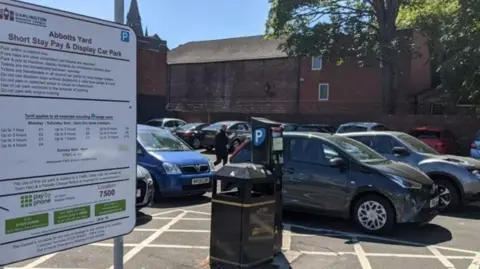 Darlington Abbotts Yard car park in Darlington with several parked cars and a black litter bin. 