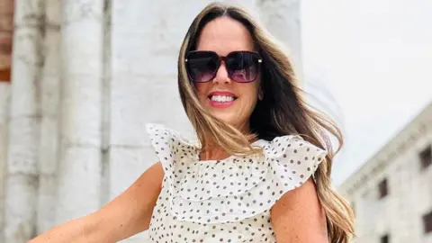 Charleston Koleji tarafından sağlanan Heather Hall, bir polka nokta elbisesinde bir fotoğraf için poz veriyor ve güneş gözlüğü takıyor.
