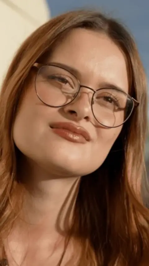 A woman with strawberry blonde hair and glasses.