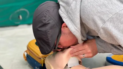 A man gives CPR to a dummy