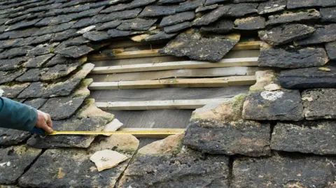 Getty Images A hole in a roof. 