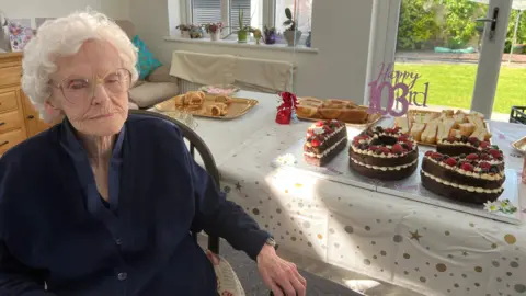 Mary-Jane Conway and some birthday treats on a table behind her