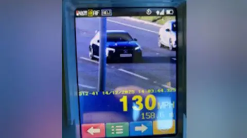 A photo of a screen where police officers have clocked a driver doing 130mph. The car appears to be a dark-coloured Mercedes. 