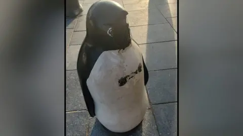 The damaged penguin bollard is missing its beak.