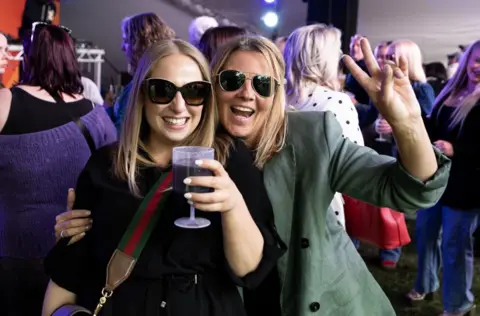 Two women in sunglasses smile at the camera at one of the smaller stages at the Cheltenham Jazz Festival