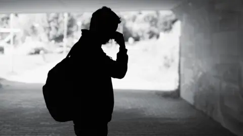 Silhouette of a man in an underpass with his hand touching his forehead
