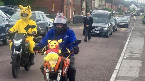 The funeral procession in Dilton Marsh including two bikers