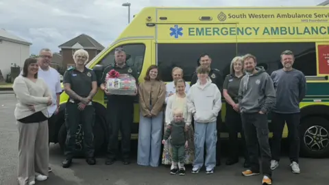 South Western Ambulance Service NHS Foundation Trust An ambulance crew with a family stood in front of a South Western Ambulance Service NHS Foundation Trust ambulance 