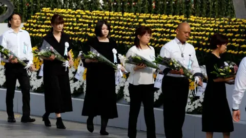 Attendees offer flowers during the Peace Memorial Ceremony on the 80th anniversary of the atomic bombing of Hiroshima