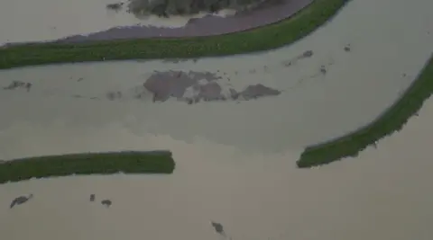 An aerial view of the banks of the Barling's Eau river, the fields surrounding the river are completely flooded.