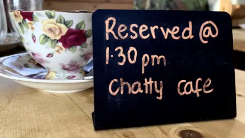 BBC A cup and saucer and a sign reserving the table for Chatty Cafe