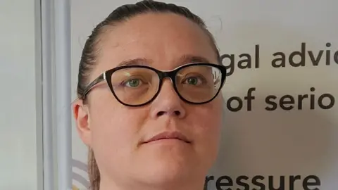 A close-up of Jolena Flett, a woman wearing dark-rimmed glasses with her dark hair pulled back