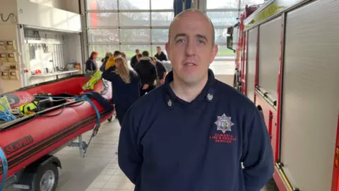 Recruitment manager Dave Love standing next to a fire engine in the fire station
