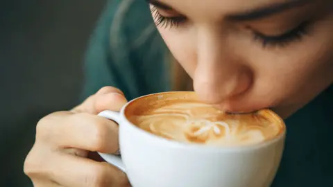 close up of a woman drinking a cup of coffee