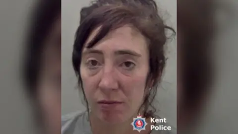 Kent Police A police mugshot of Nina Mercer. She is wearing a beige jumper and has dark hair that is partly tied up.