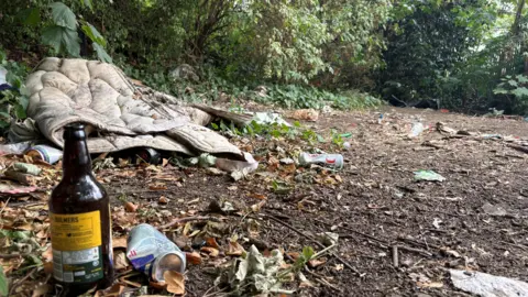 Ben Schofield/BBC Rubbish on the ground, including a dirty duvet, a bottle and a tin can.