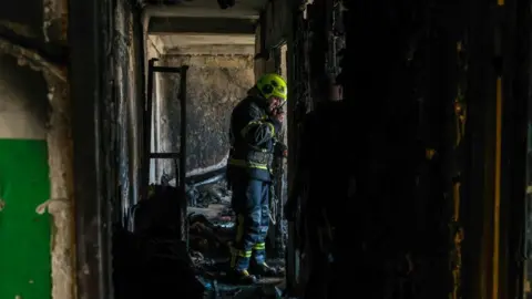 Firefighter stands inside of a home in a high-rise in Kyiv, Ukraine