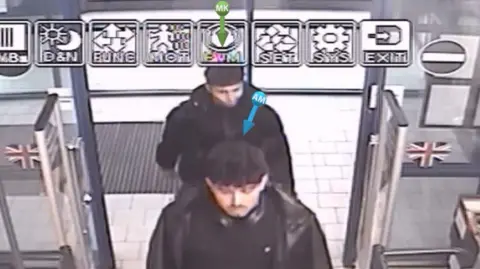 CCTV FOOTAGE of two young men dressed in black walking into a store