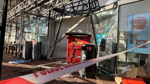 Police tape crosses a pavement outside a shuttered Co-op store, which also has scaffolding around it